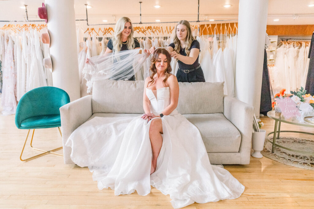 Staff of belle en blanc assisting bride during dress try on.