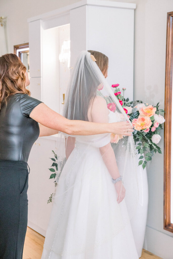 Staff member of Belle en Blanc in Billings Montana helping a bride with her veil.