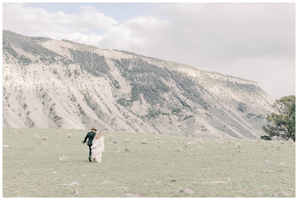 Bride and groom running for wedding photographs in Yellowstone park.
